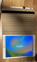 iPad powered on inside beige folio with Apple Pencil above