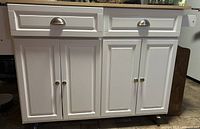 Front view showing two drawers, four paneled doors, metal hardware, casters