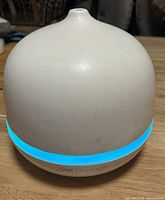 Front view of white Saje aromaOm diffuser with blue LED ring lit