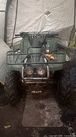 Front view of green Yamaha Wolverine ATV showing headlights, brush guard, front rack, tires
