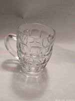 Full view of clear glass dimpled beer mug with handle
