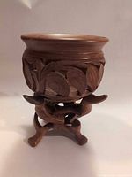 Bowl seated on stand, front view highlighting leaf carving and overall form