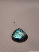 Front view showing triangular cabochon shape and blue flash