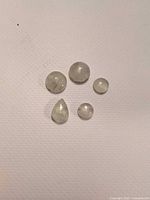 Five pale green cabochons arranged on white background