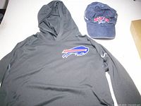 Hoodie laid flat showing Bills logo and cap positioned beside