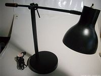 Left side view of black adjustable desk lamp on base, power cord visible