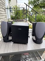 Insignia subwoofer with two Harman Kardon satellites on tabletop