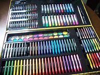 Open multimedia art set showing pastels, markers, watercolors, brushes
