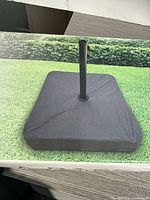 box displaying black square offset umbrella base on lawn
