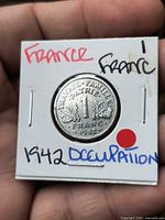 Obverse view of 1942 1 Franc coin in holder showing denomination and oak sprigs