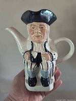 Front view of ceramic Toby jug teapot held in hand