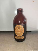 Full view of amber glass Guinness bottle standing upright showing front label