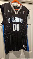Full front view of black Orlando Magic jersey on hanger