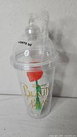 Front view of clear tumbler with lid, straw, and rose accent
