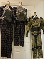 Front view of three hanging costumes, two Minecraft suits and one Halo Master Chief suit