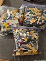 Three gallon bags of assorted LEGO pieces displayed on couch