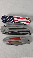 Three closed pocket knives side by side showing handle designs