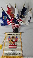 Group view of six miniature military branch flags plus U.S. flag on black stand