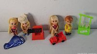 Group shot of four dolls with five accessories