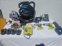 Entire lot displayed on table including all tools, batteries, charger, vacuum and accessories
