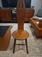 front view showing carved tall back, round seat, legs