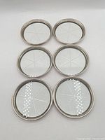 Six round coasters laid out face up showing sterling rims and star cut centers