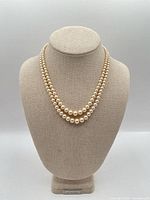 Full view of double-strand cream pearl necklace displayed on bust