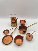 Group view of entire copper and brass miniature cookware set