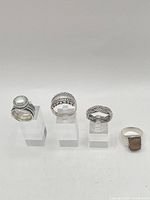 Four sterling silver rings on acrylic stands