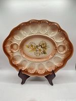 Full view of ceramic deviled egg plate on stand, showing color gradient and egg recesses