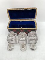 Open tartan case showing blue interior and three clear glass perfume bottles with stoppers
