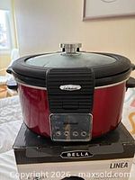 Front view of red Bella Linea multicooker on original box, showing control panel and lid