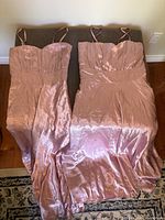 Front view of both blush satin gowns laid flat