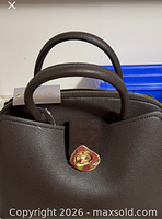 Front view showing brown leather, rolled handles, turn-lock, hang tag