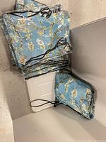 Stack of sealed Almond Blossom drawstring backpacks in box