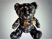 Front view of black plush bear with skeleton print and bow
