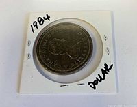 Obverse of 1984 Canadian dollar in flip, handwriting visible