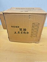 sealed brown shipping carton with line art of five-tier organizer