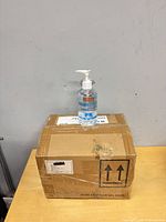 Closed cardboard box with one sample sanitizer bottle on top