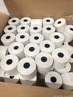 Open carton showing multiple white thermal paper rolls