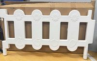 Front view of one white plastic fence panel showing openings and motifs