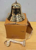 Bell exterior showing HAPPY HOUR engraving on cardboard box with bracket wrapped beside it
