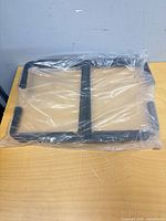 Packaged pair of black ceiling storage hooks in plastic wrap on table