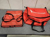 two red insulated bags side by side showing size difference and branding