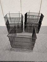 Three of the black wire pegboard baskets showing square shape and hooks