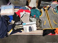 Overview of entire lot showing diapers, clothing items and packaged underwear-sock set