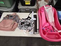 Lot overview showing diaper bag, exerciser components and bathtub