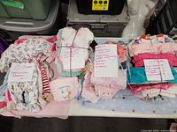 Four tied bundles of infant clothing on table with handwritten inventory notes