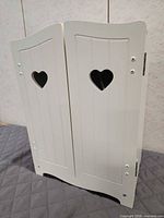 front view of white wooden armoire with heart cutouts