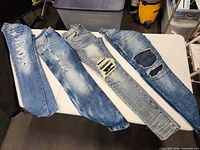 Five pairs of jeans laid out on table showing colors and distress levels